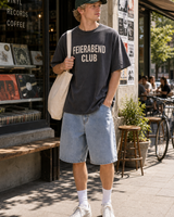 Germany Feierabend Club graphic set sunny model scene with charcoal tee green cap natural canvas tote and washed shorts