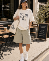 Not My Cup Of Tea graphic set sunny model scene with cream tee cap natural canvas tote and washed shorts