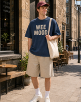 Scotland Wee Mood graphic set sunny model scene with navy tee burgundy cap natural canvas tote and washed shorts